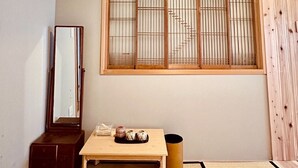 A traditional Japanese room with tatami flooring, a low wooden table with decorative items, a mirror, and a shoji screen.