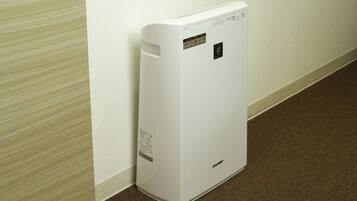 A white portable heater against a wall with a carpeted floor.