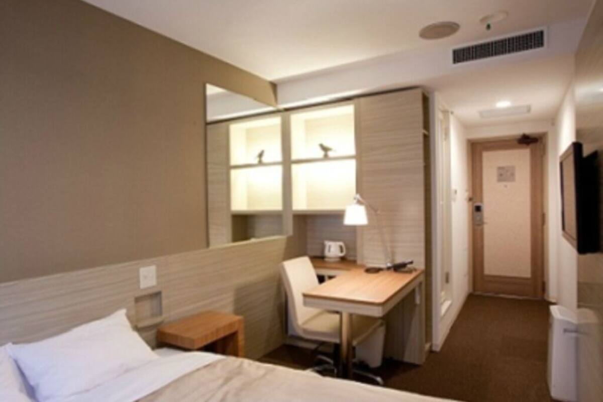 Ein Hotelzimmer mit einem Bett, einem Schreibtisch, einem Stuhl, einer Lampe und einem Fernseher.