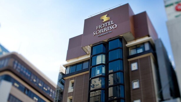 Un hôtel appelé Hotel Sorriso, doté d’une architecture moderne, se distinguant par une enseigne bien visible et des fenêtres en verre réfléchissant la lumière.