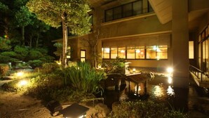 Un bâtiment agrémenté d’un élément décoratif aquatique à l’avant, entouré de verdure.