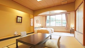 Une chambre d’hôtel dotée d’un grand lit, d’un coin salon avec une table et des chaises, d’une fenêtre avec des rideaux et d’une vue sur l’extérieur.