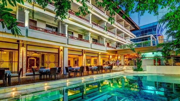 Ein Hotel mit Pool, Essbereich im Freien und mehreren Balkonen.