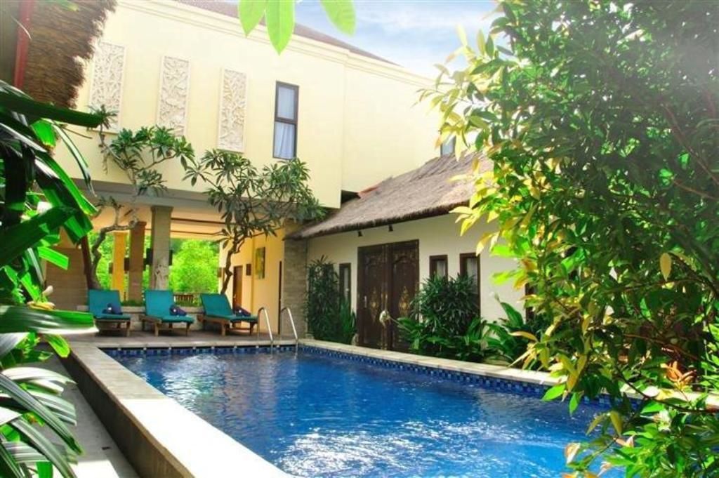 A pool area with lounge chairs and a building with a thatched roof.