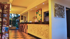 Una hall d'albergo con pavimento a scacchi, una reception e una parete con un dipinto floreale.