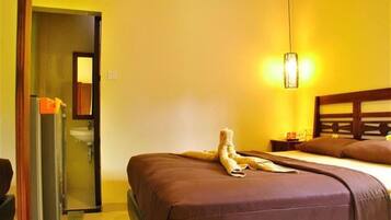 Quarto de hotel com uma cama, mesa de cabeceira, luminária e espelho.