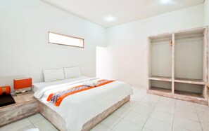 Habitación de hotel con cama, armario, una mesita con lámpara y un cuadro en la pared.