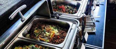 A buffet with multiple food stations, including rice dishes and stir-fries.
