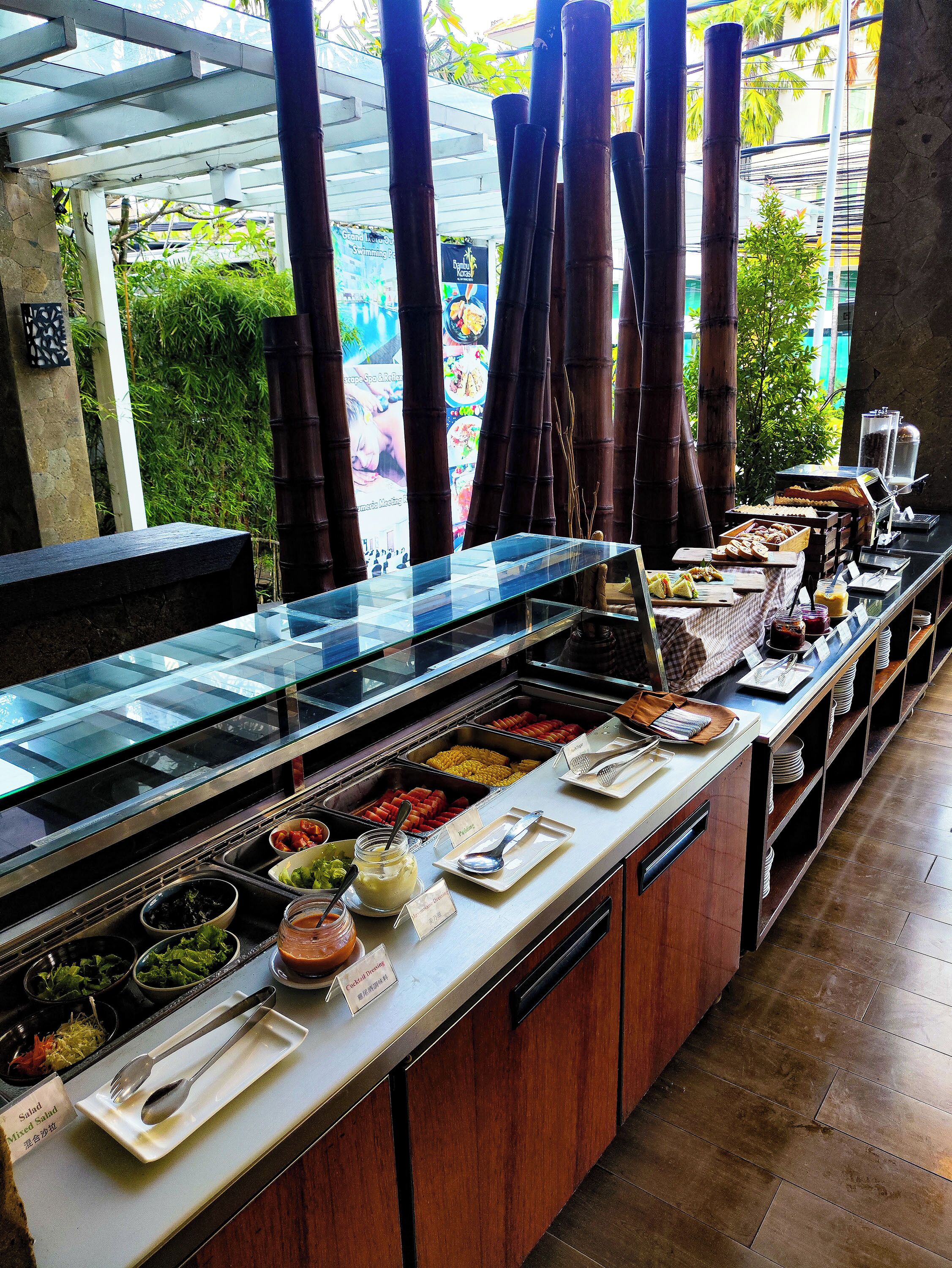 A buffet with various food options, a coffee station, and a view of greenery outside.