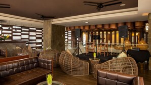 A spacious lobby with leather sofas, wicker chairs, and a stage with musical instruments. - Grand Ixora Kuta Resort (Kuta)