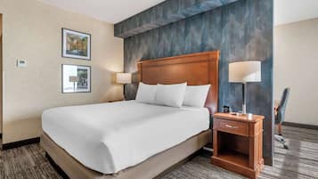 A hotel room with a large bed, two bedside tables, a desk, and a chair.