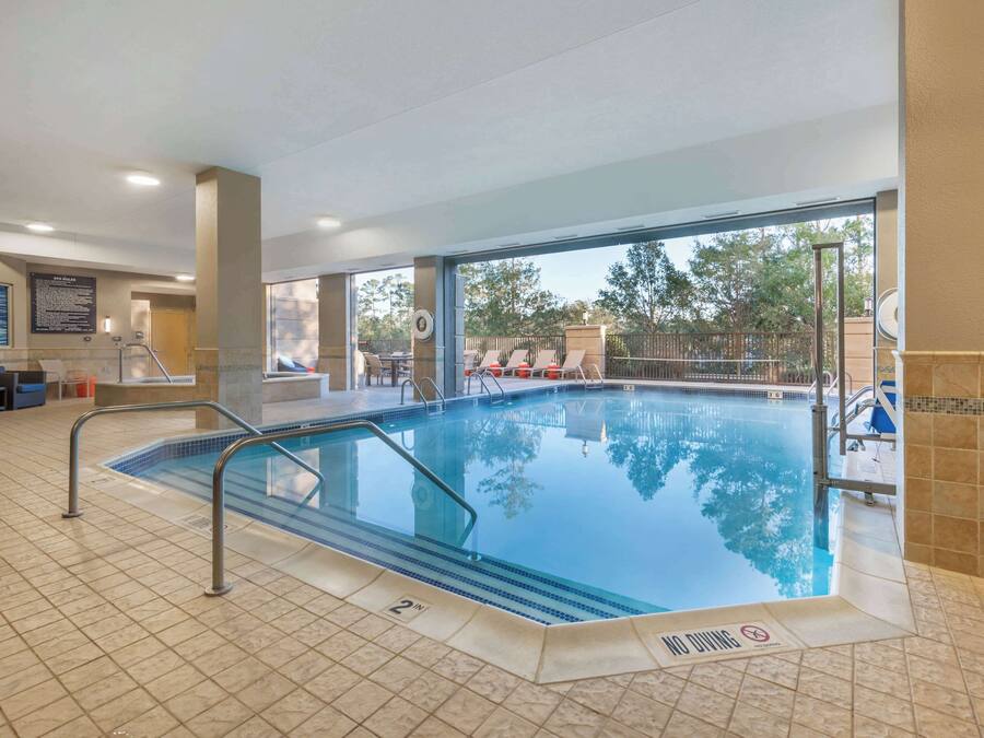 A swimming pool with clear blue water, a tiled floor, and a 'No Diving' sign.