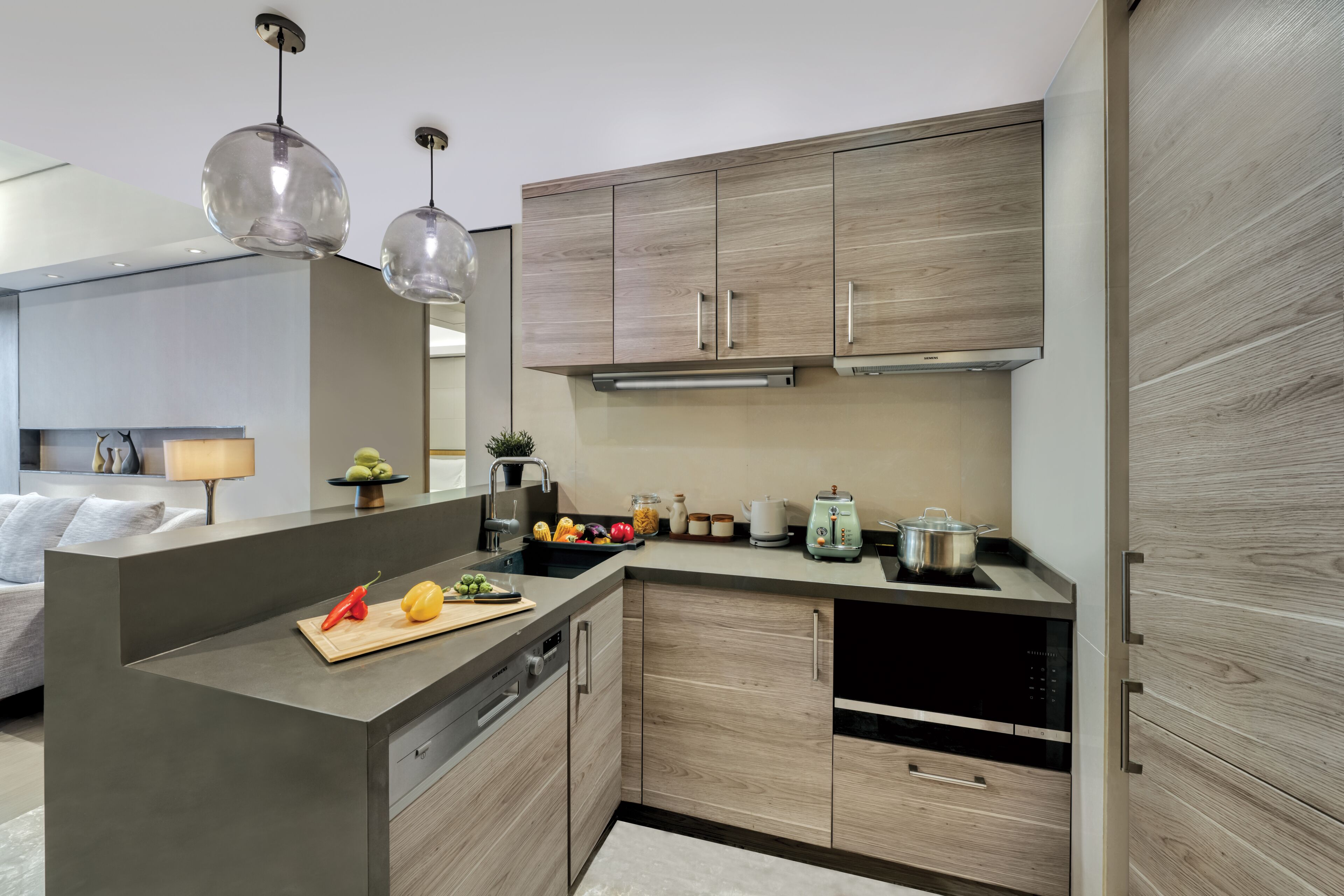 Une cuisine moderne avec des meubles en bois, un îlot central et un coin repas comprenant un canapé et une lampe.