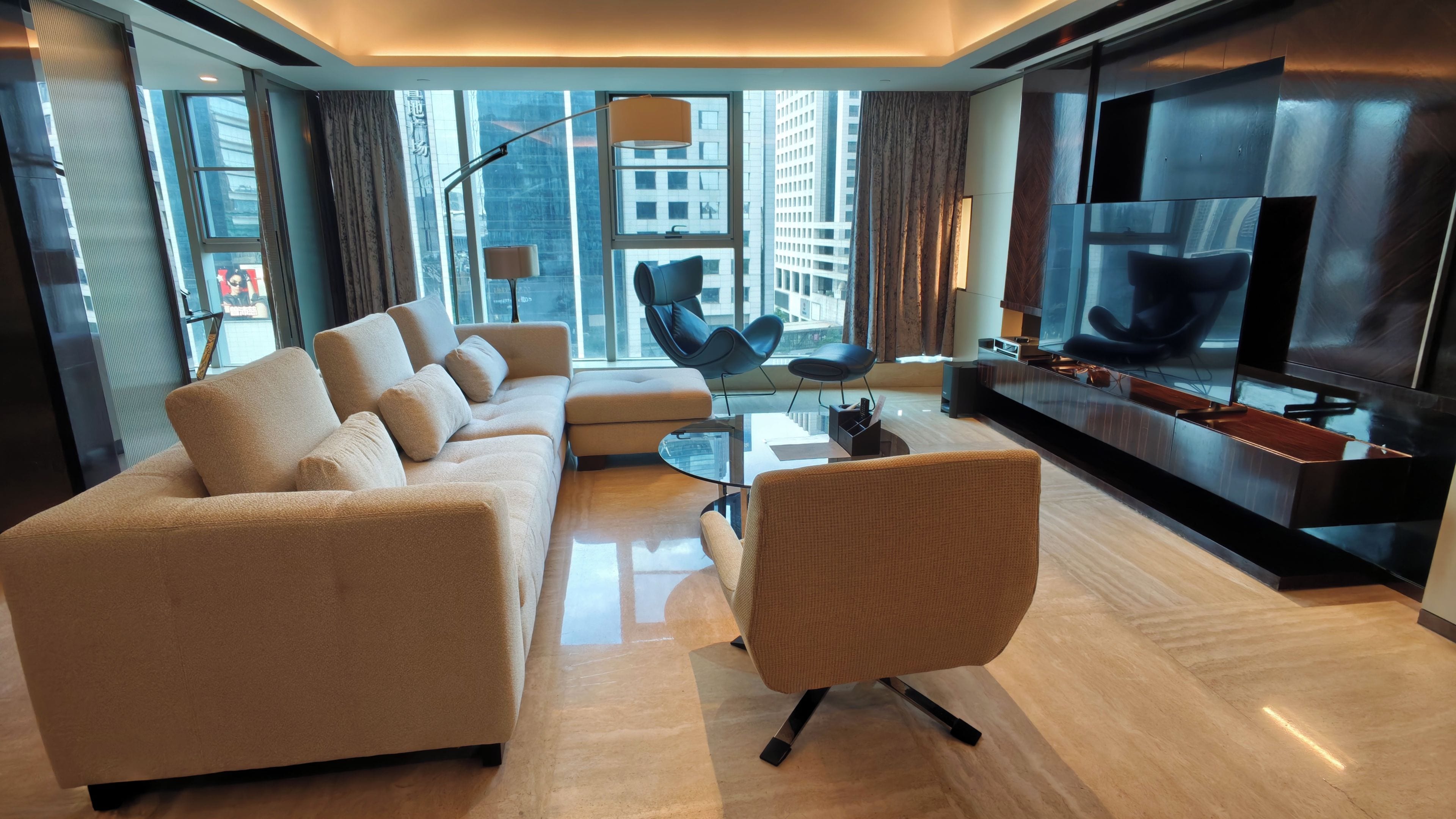 A modern living room with a sofa, armchairs, a coffee table, and a TV.