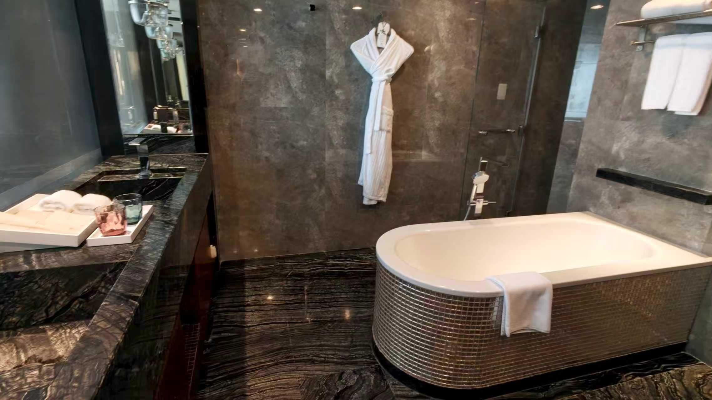 A modern bathroom with a freestanding bathtub, a marble countertop, and a towel rack.