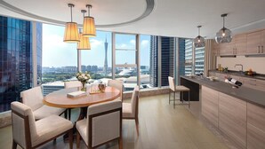 A modern kitchen with a large island, a dining area with a round table and chairs, and large windows offering a city view. - Ascott IFC Guangzhou (Guangzhou)