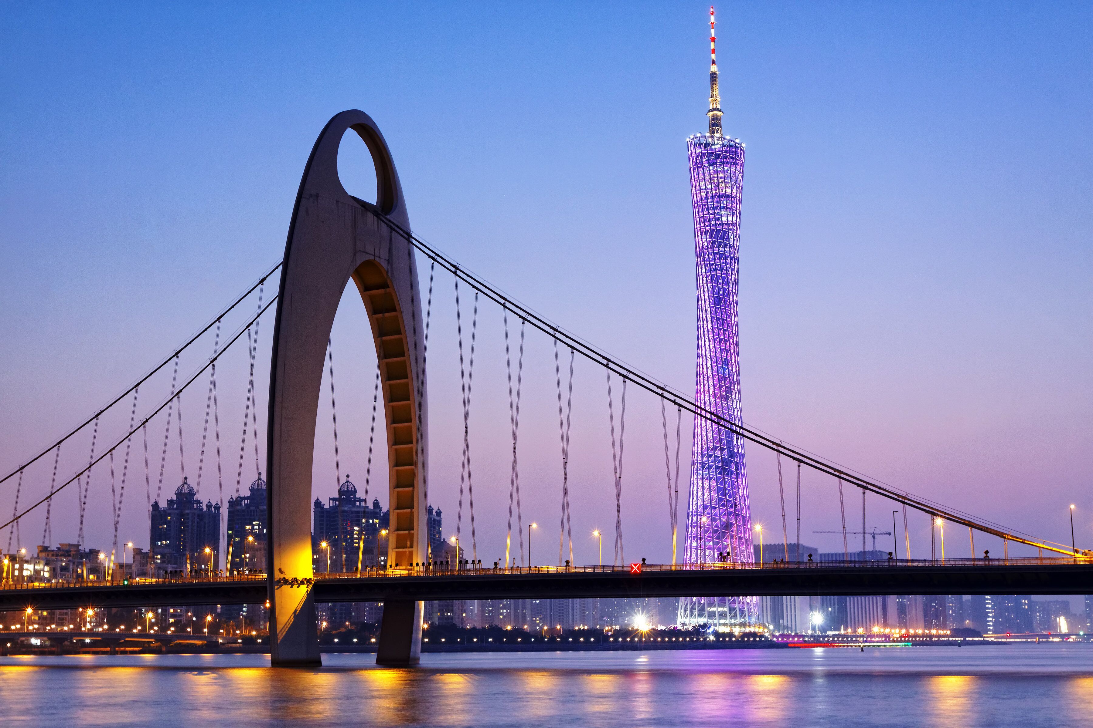 A bridge with a large arch and a tall tower in the background.