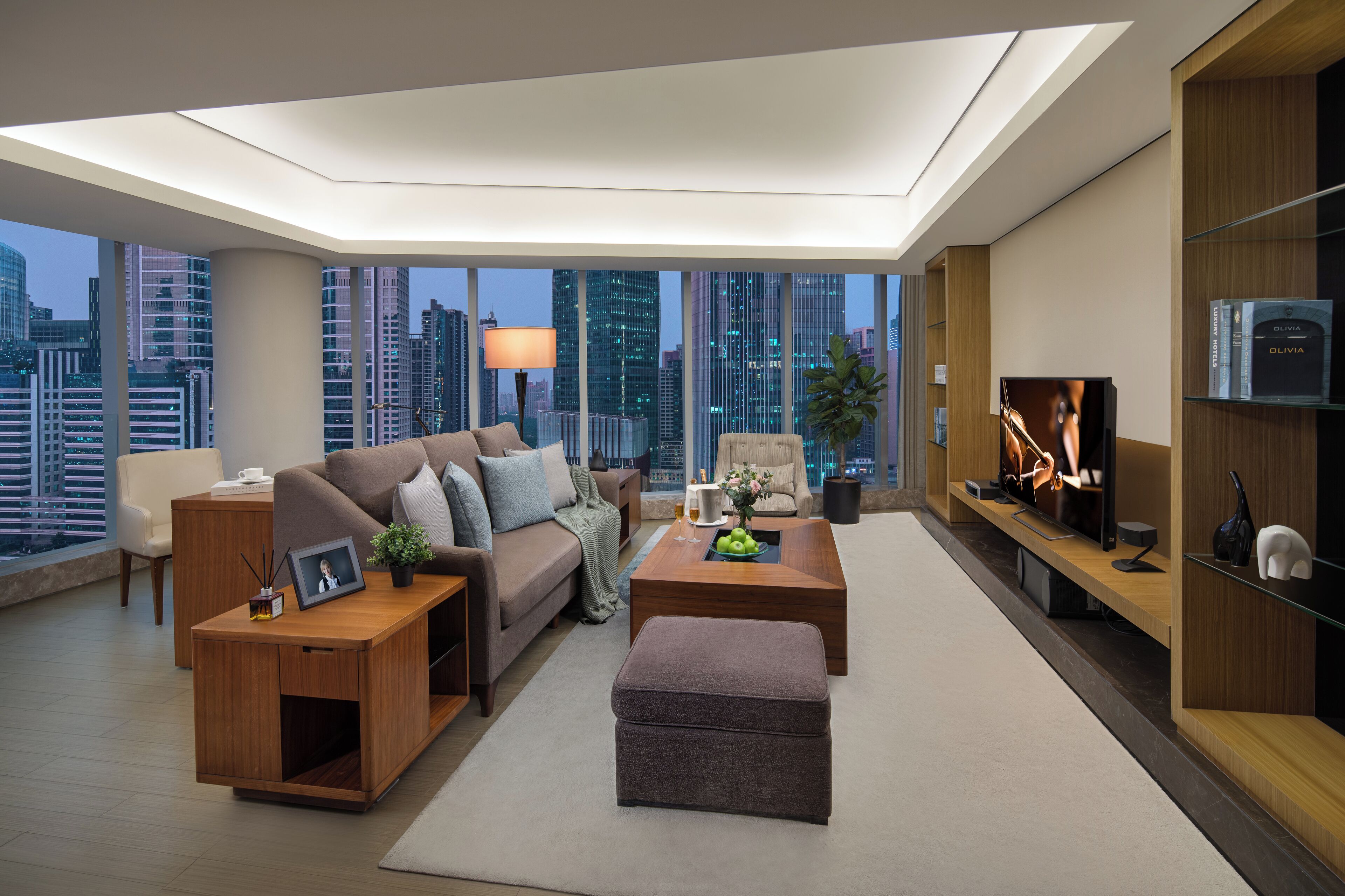 A modern living room with a city view, a sofa, a coffee table, and a TV.