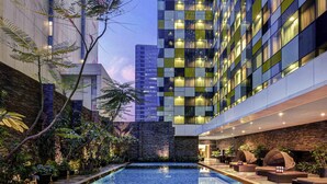 Un hôtel moderne doté d’une piscine, d’une végétation luxuriante et d’une architecture contemporaine.