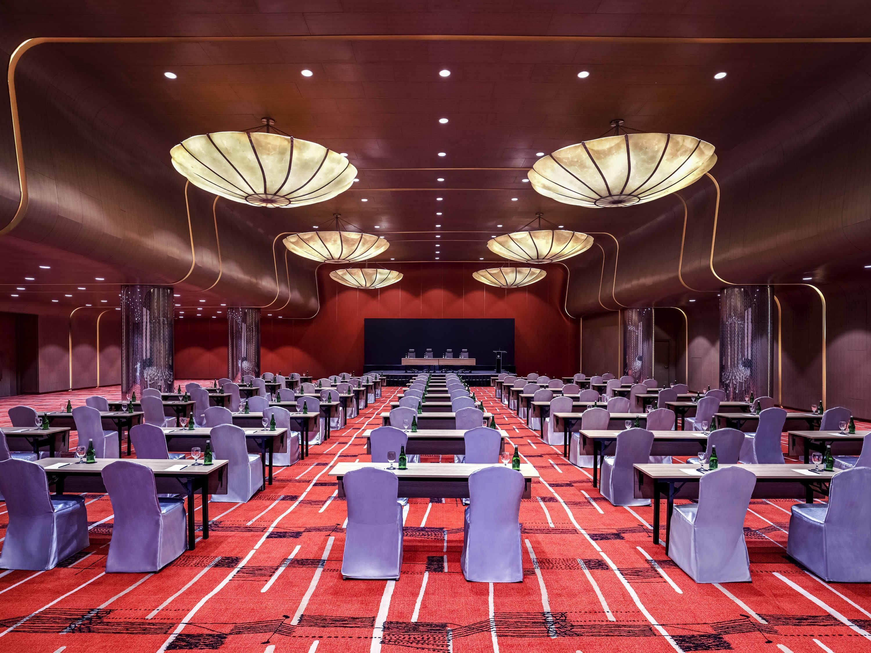 A conference room with tables, chairs, and a stage.