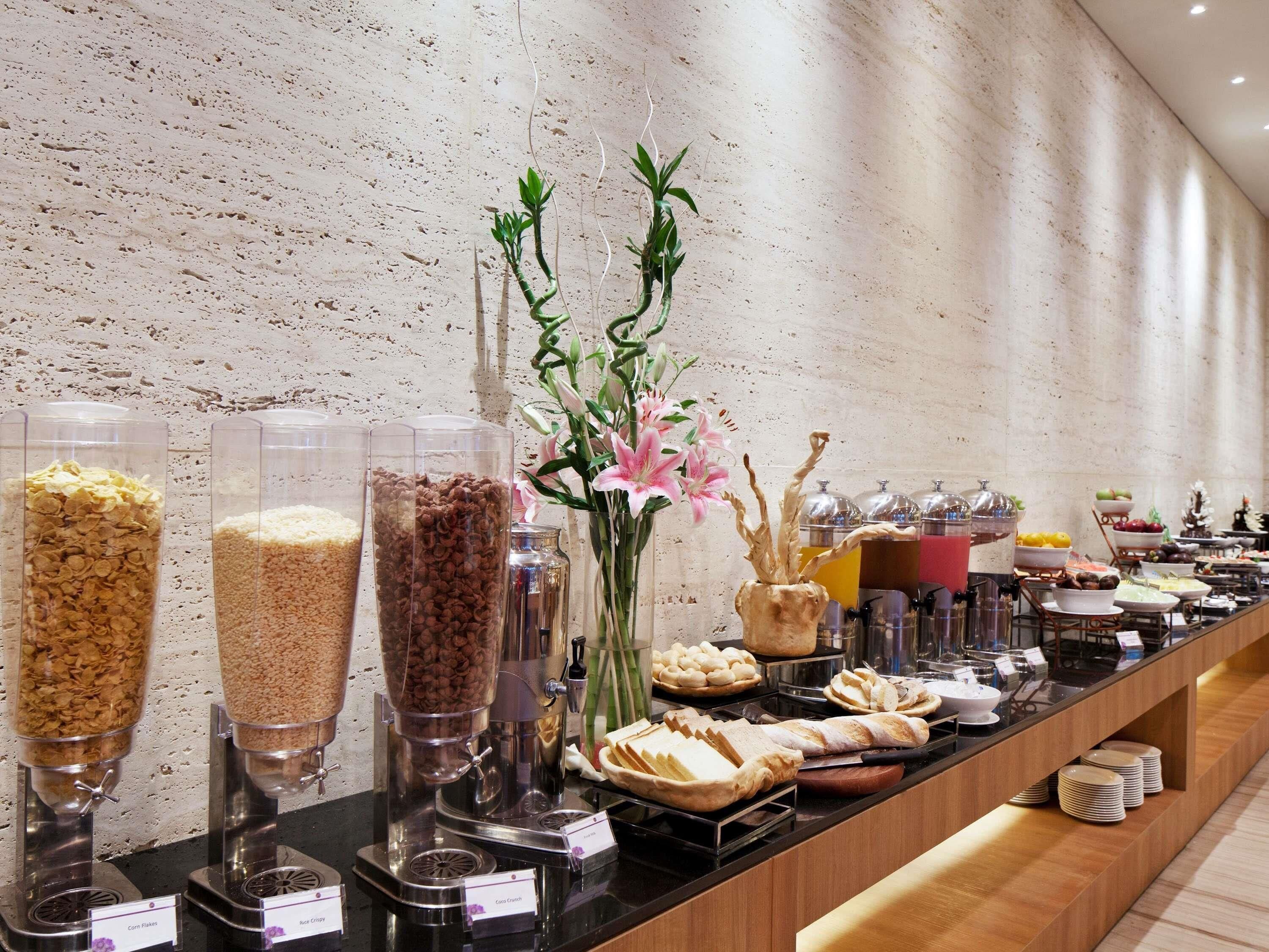 A buffet with various food items and a decorative vase of flowers.