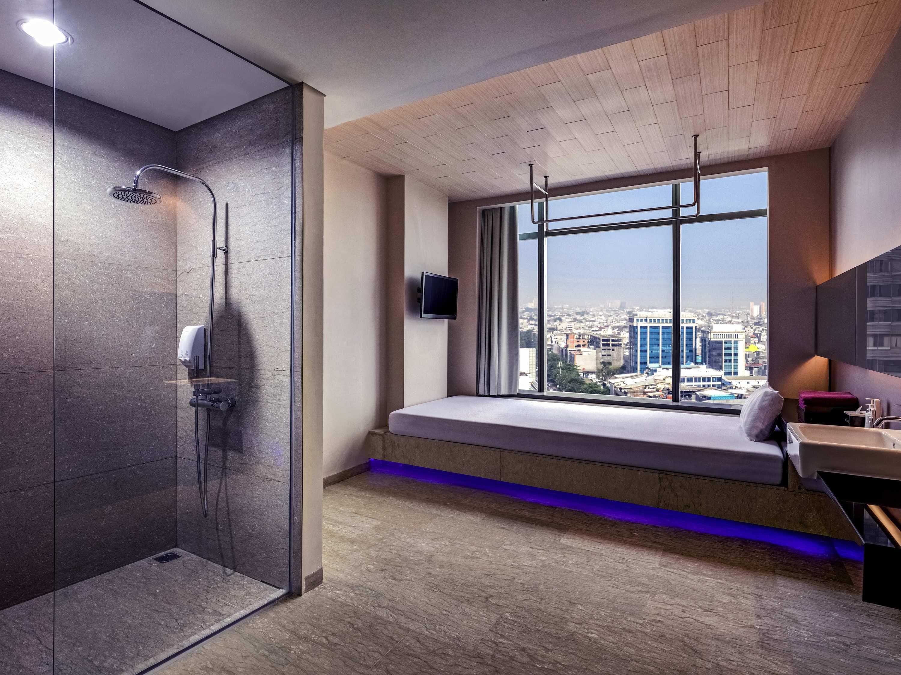 A modern bathroom with a shower, a window with a city view, and a built-in bench.