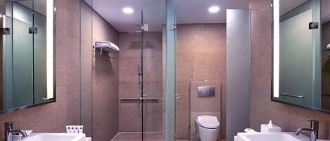 A modern bathroom with two sinks, a glass shower enclosure, and a toilet.