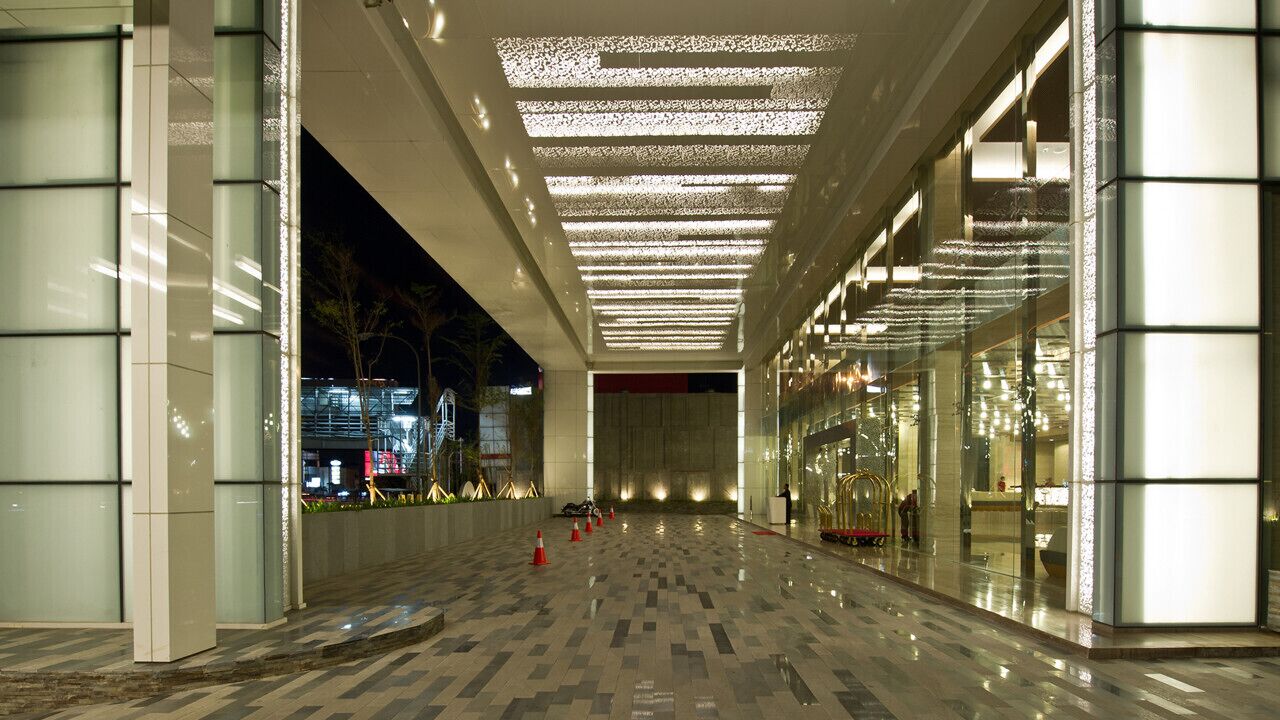 Un corredor interior amplio con suelo reflectante, paredes de vidrio y techo con diseño.