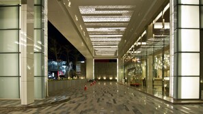 Un corredor interior amplio con suelo reflectante, paredes de vidrio y techo con diseño.