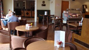 A restaurant with wooden tables and chairs, a buffet area, and a no smoking sign on the wall.