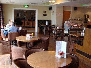 A restaurant with wooden tables and chairs, a buffet area, and a no smoking sign on the wall.