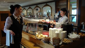 A bar area with a counter, a coffee machine, and a display of pastries. - Ard Ri House Hotel (Tuam)