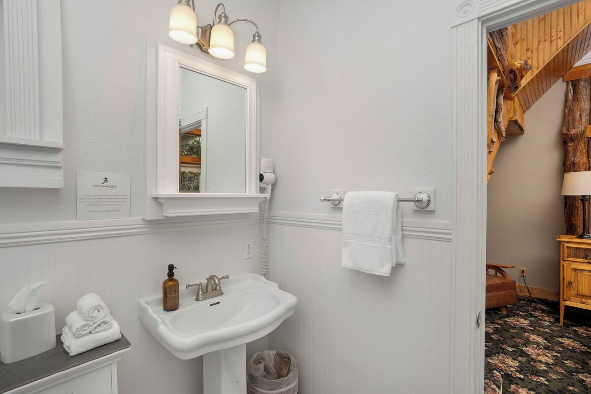 A bathroom with a white sink, mirror, and towel rack.