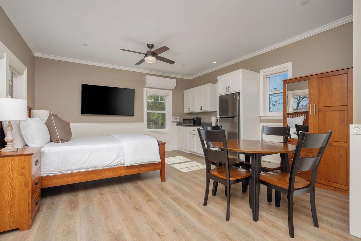 A bedroom with a bed, bedside table, and a TV mounted on the wall.