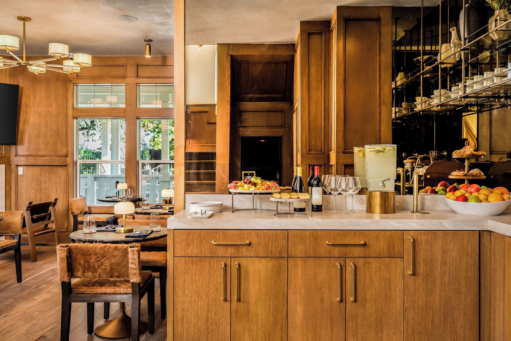A modern kitchen with wooden cabinets, a marble countertop, and a dining area with leather chairs.