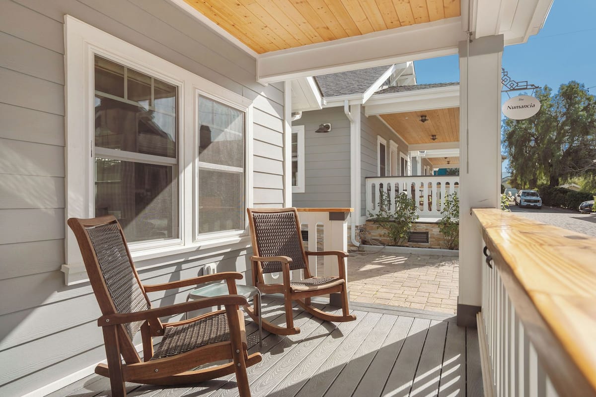 A wooden deck with two rocking chairs and a wooden railing.