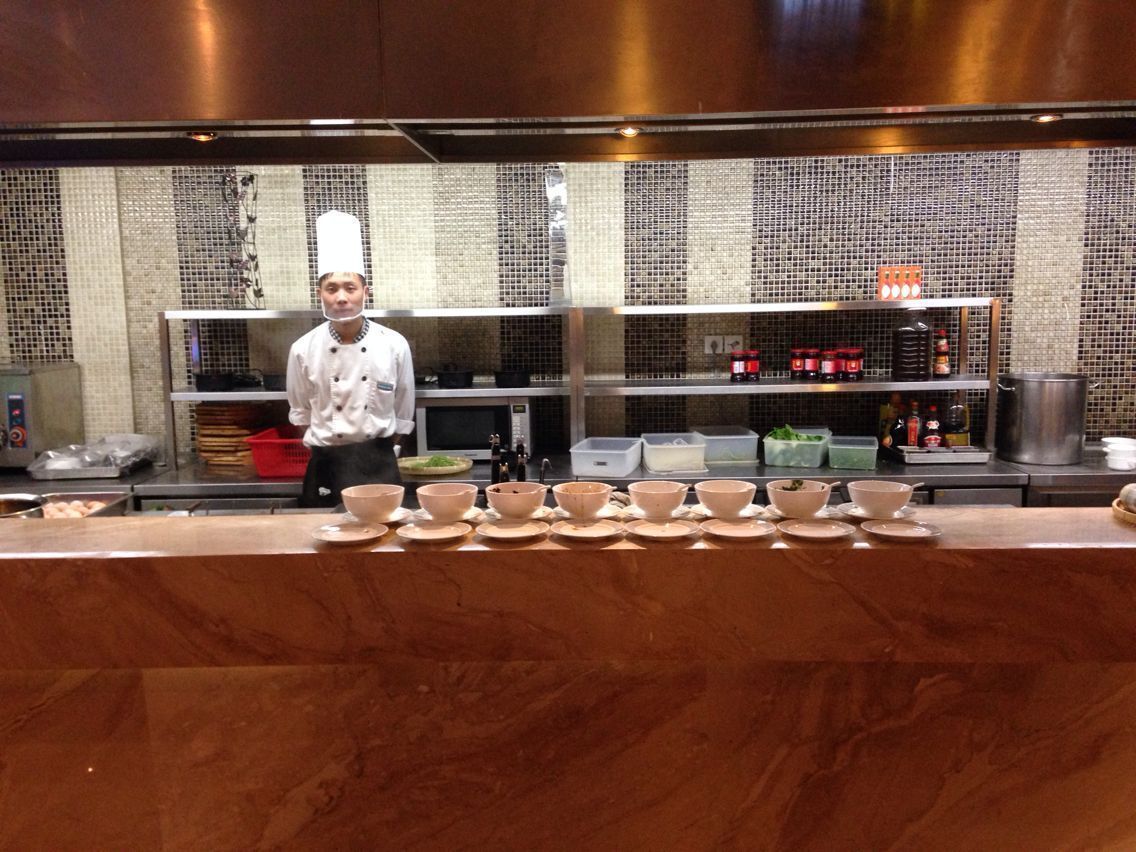 A chef standing behind a counter with multiple bowls and kitchen utensils.