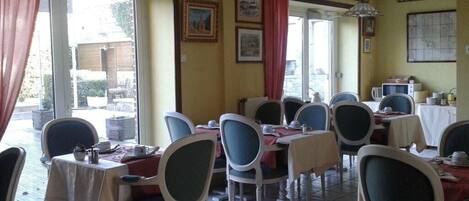 Un comedor con mesas y sillas, vistas al exterior y un ventilador de techo.