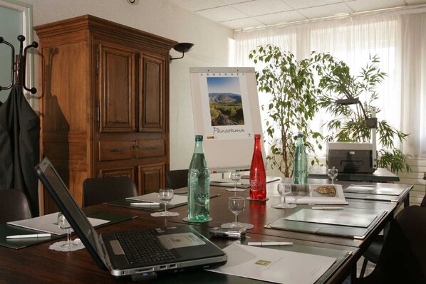 A conference room with a wooden cabinet, a poster, and a table set for a meeting. - Le Val Saint Hilaire (Givet)