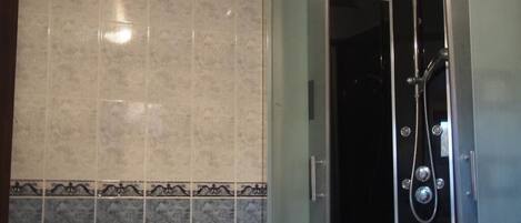 A bathroom with a glass-enclosed shower, a tiled wall, and a towel rack.