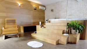 A modern interior with a wooden bench, a fireplace, a staircase, and a potted plant.