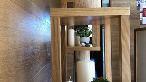 A wooden shelf with candles and a potted plant.