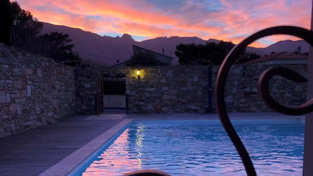 A pool with a stone wall and a metal spiral structure in the foreground.