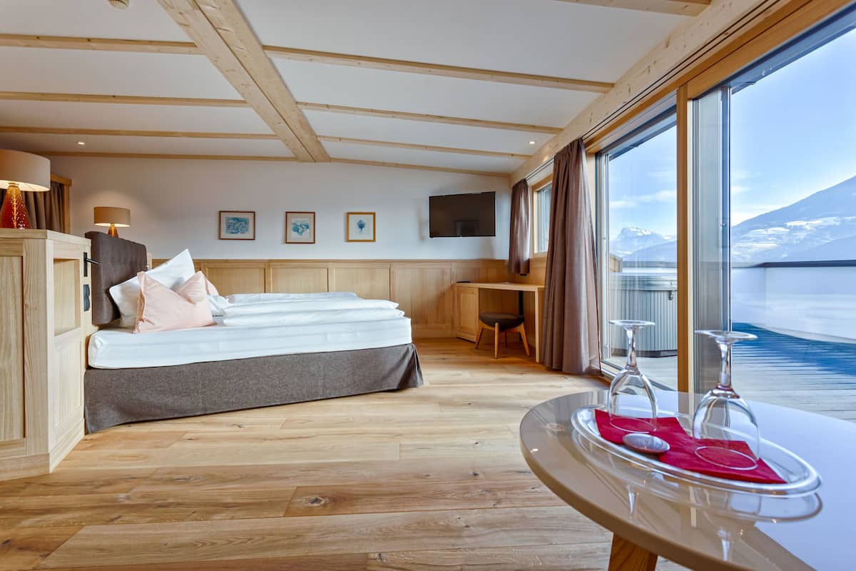 A modern room with a bed, desk, and large windows offering a view of a snowy landscape.