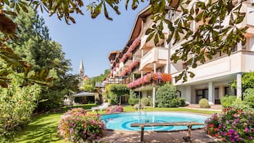 Relax in our serene garden, surrounded by lush greenery and vibrant flowers, with a refreshing pool and picturesque views from the hotel's balconies.