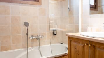 Een moderne badkamer met een bad, douche en wastafel.