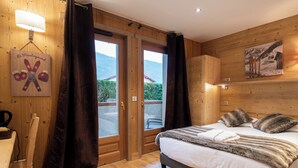A wooden-paneled room with a bed, a lamp, a window, and a door. - La Ferme du Lac (Thyez)