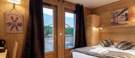 A wooden-paneled room with a bed, a lamp, a window, and a door.