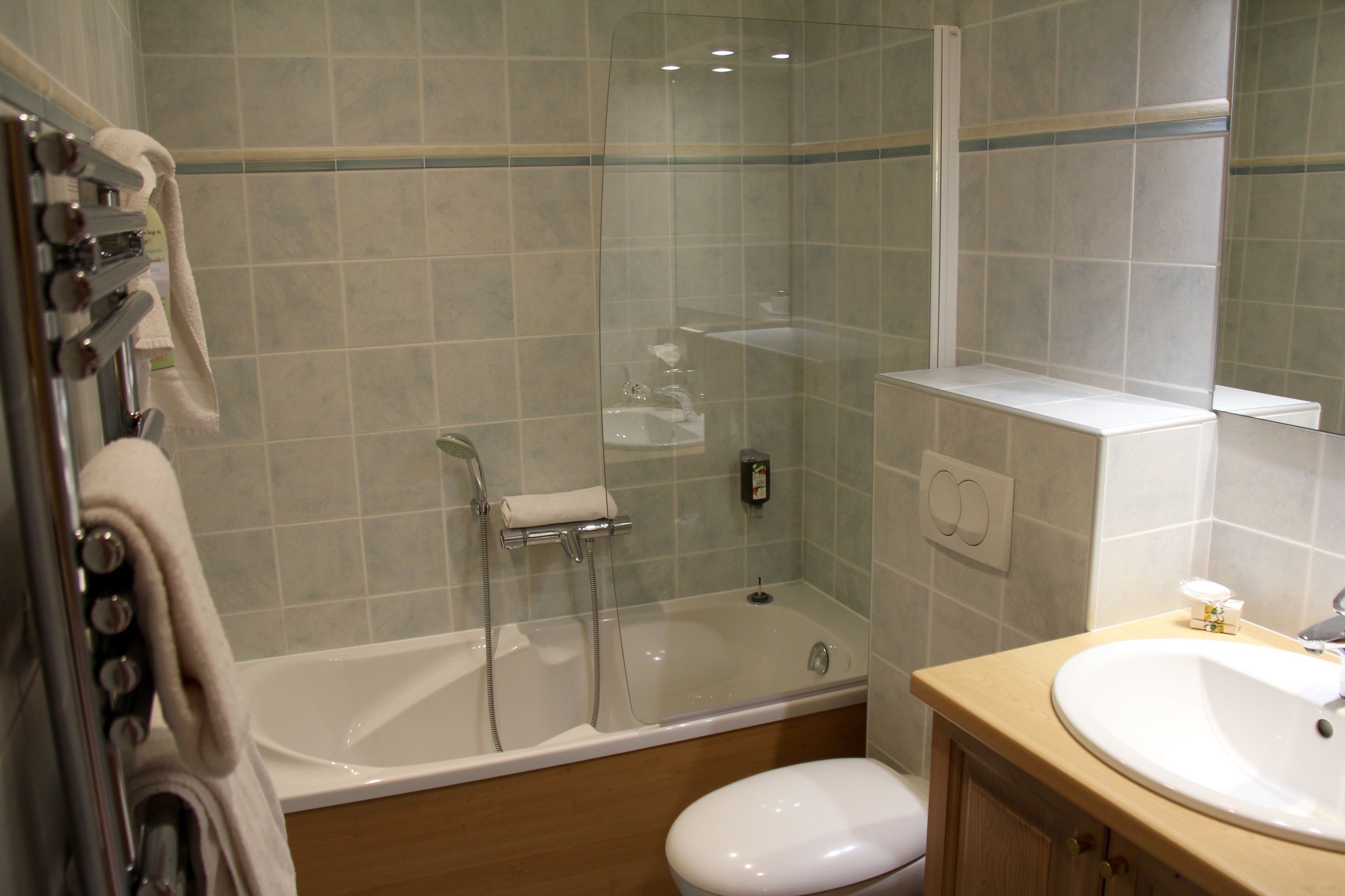 A bathroom with a glass-enclosed shower, a white bathtub, a sink, and a toilet.