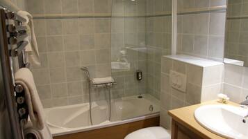A bathroom with a glass-enclosed shower, a white bathtub, a sink, and a toilet.